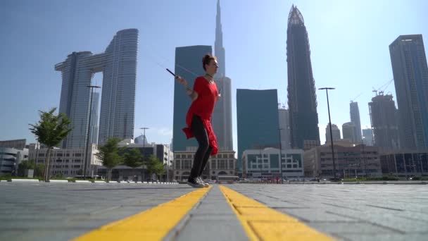 Jovem pulando com corda de salto com fundo cityscape de Dubai em câmera lenta — Vídeo de Stock