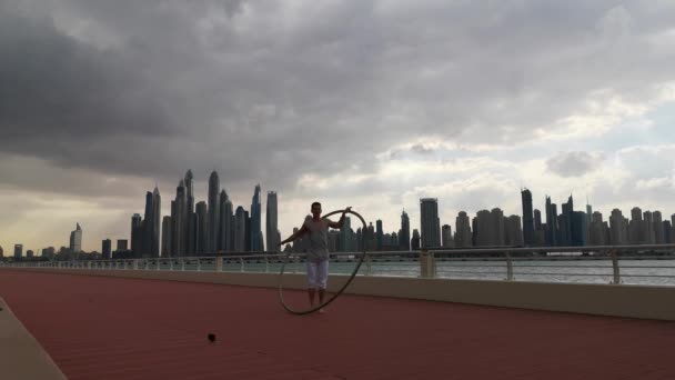 Cyr Wheel umělec s cityscape pozadí Dubaje během západu slunce — Stock video