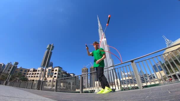 Uomo che salta con corda di salto sullo sfondo paesaggio urbano di Dubai. Rallentatore — Video Stock