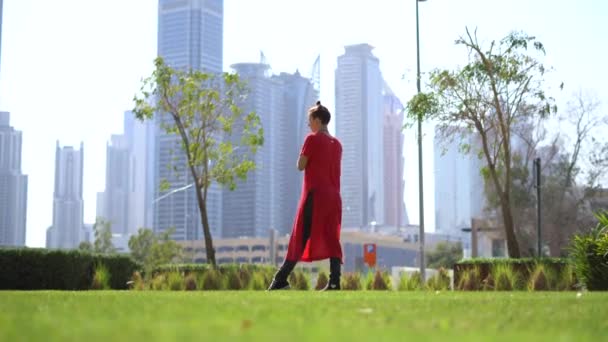 Mladá dívka skákání s švihadlem na zelené trávě s cityscape pozadí Dubaje — Stock video