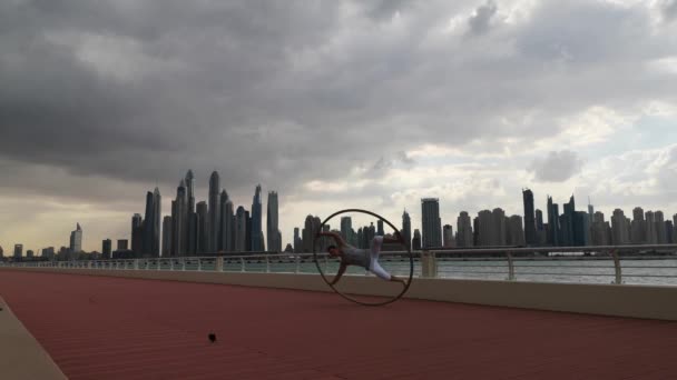 Cyr Wheel umělec s cityscape pozadí Dubaje během západu slunce — Stock video