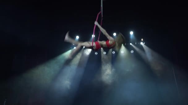 Acrobate féminin mince et sexy sur la scène avec cerceau aérien avec des projecteurs sur le fond — Video