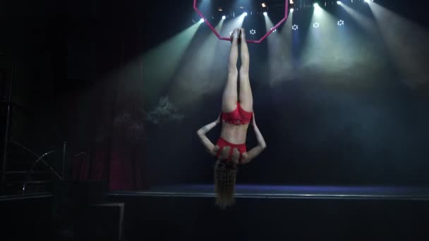 Sottile e sexy acrobata femminile aerea sul palco con cerchio aereo con luci spot sullo sfondo — Video Stock