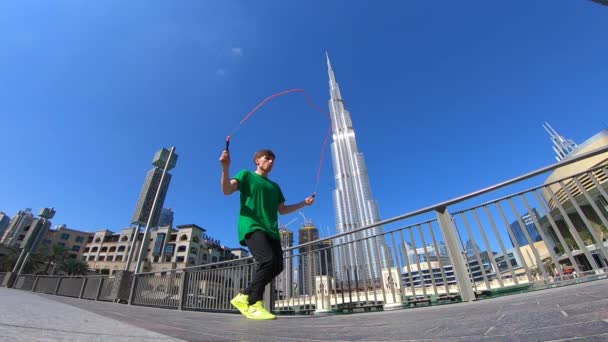 在迪拜的城市景观背景上跳着跳绳的人。慢动作 — 图库视频影像