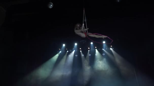 Slanke en sexy vrouwelijke antenne acrobaat op het podium met antenne hoepel met spots op de achtergrond — Stockvideo