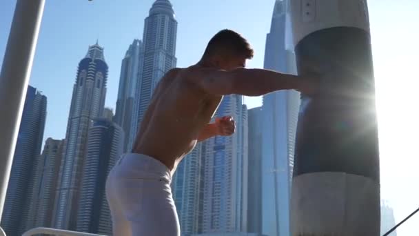 Muscular Man uderza worek bokserski z pejzażem Dubaju na tle — Wideo stockowe