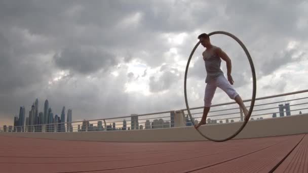 Cyr Wheel καλλιτέχνης με φόντο αστικό τοπίο του Ντουμπάι κατά τη διάρκεια του ηλιοβασιλέματος — Αρχείο Βίντεο