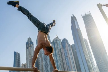 Kaslı bir adam Dubai 'nin arka planında gökdelenlerin manzarasıyla sokakta egzersiz yapıyor. Sağlıklı yaşam tarzı ve modern anlayışı
