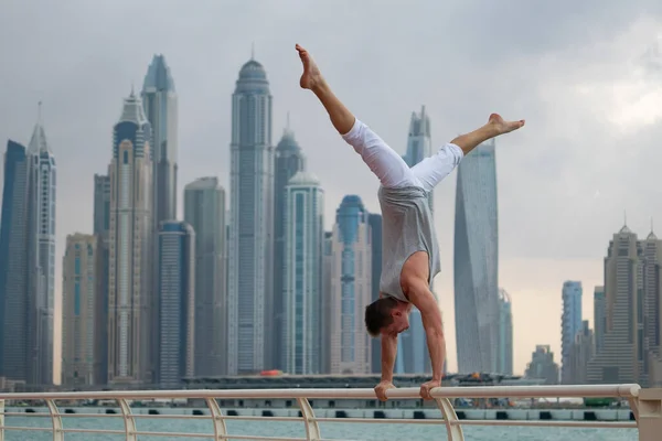 Hombre musculoso haciendo ejercicio en la calle con paisaje urbano de rascacielos en el fondo en Dubai. Concepto de estilo de vida saludable y moderno — Foto de Stock