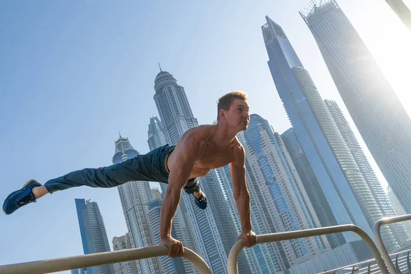 Μυώδης άνθρωπος κάνει προπόνηση στο δρόμο με το αστικό τοπίο των ουρανοξυστών στο παρασκήνιο στο Ντουμπάι. Έννοια του υγιεινού τρόπου ζωής και σύγχρονο — Φωτογραφία Αρχείου