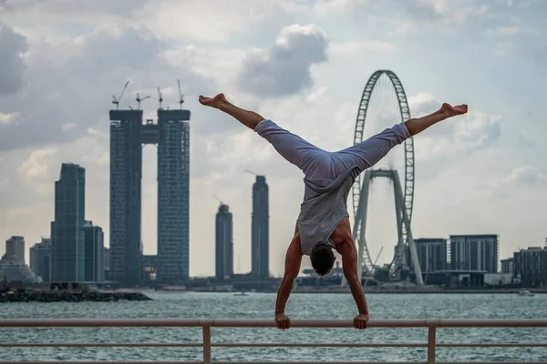 Muscular man doing workout on the street with cityscape of skyscrapers on background in Dubai. Concept of healthy lifestyle and modern — Stock Photo, Image