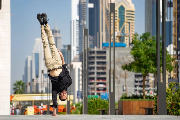 Acrobat κρατήσει ισορροπία ένα τα χέρια με θολή πόλη Ντουμπάι cityscape. Έννοια της σύγχρονης, των επιχειρήσεων και απεριόριστη δυνατότητα — Φωτογραφία Αρχείου