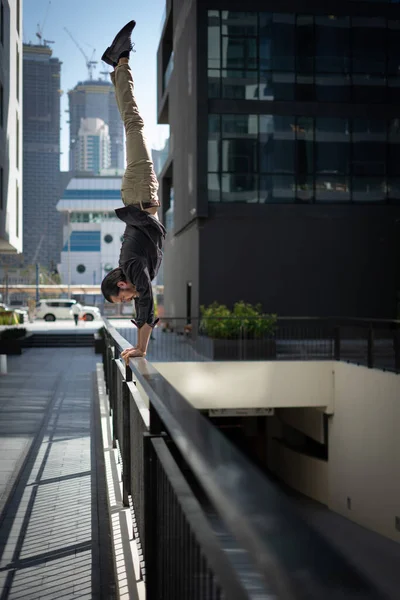 Acrobat keep balance one the hands with blurred Dubai cityscape. Concept of modern, business and unlimited possibility