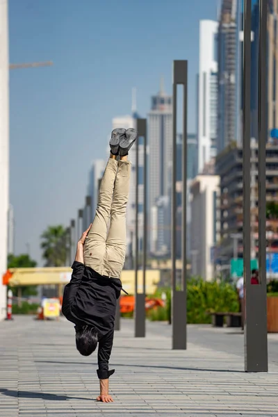 アクロバットは、手と手のバランスを保つぼやけたドバイの街並み。現代的、ビジネス的、無限の可能性の概念 — ストック写真