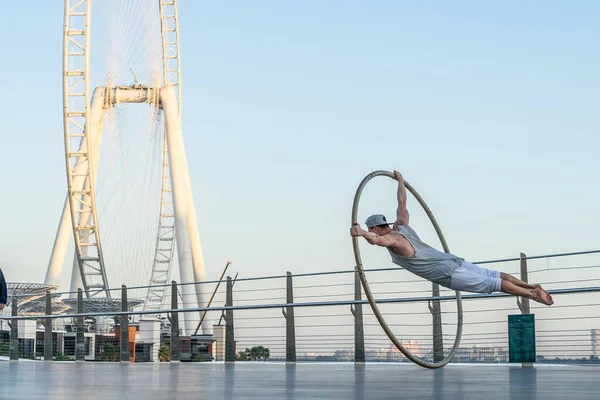 Ντουμπάι, Φεβρουάριος 2020. Cyr Wheel καλλιτέχνης με τροχό Ferris στο παρασκήνιο του Ντουμπάι κατά τη διάρκεια του ηλιοβασιλέματος — Φωτογραφία Αρχείου