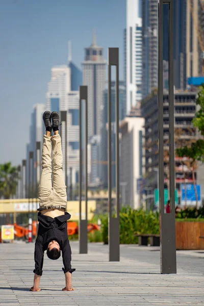 Acrobat keep balance one the hands with blurred Dubai cityscape. Concept of modern, business and unlimited possibility