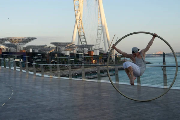 Dubai, februari 2020. Cyr Wheel artist med pariserhjul på bakgrunden av Dubai under solnedgången — Stockfoto