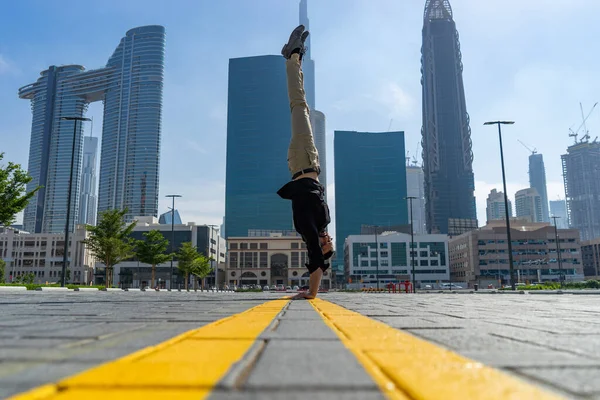 Acrobat mantener el equilibrio de una de las manos con el paisaje urbano borroso de Dubai. Concepto de posibilidad moderna, de negocios e ilimitada — Foto de Stock