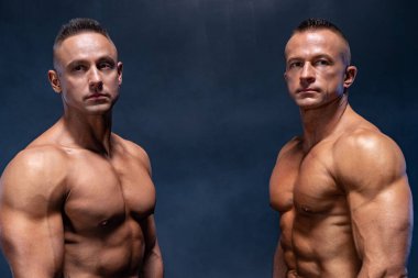 Siyah arka planda izole edilmiş iki kaslı adam. Güçlü erkek çıplak gövde kasları