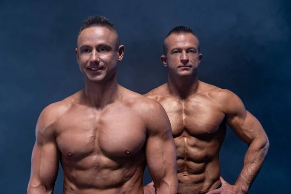 Zwei muskulöse Männer isoliert auf schwarzem Hintergrund. Starker männlicher nackter Oberkörper — Stockfoto