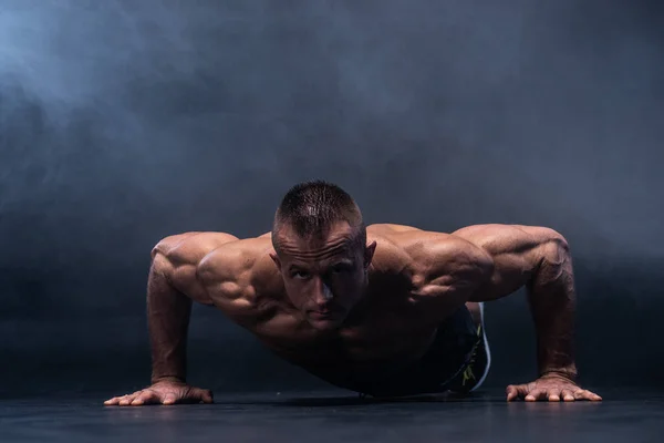 Hombre muscular haciendo ejercicio calisténico aislado sobre el fondo negro —  Fotos de Stock