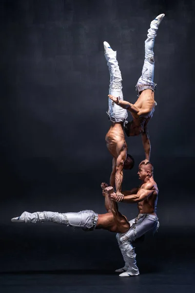 Vier gespierde man voeren moeilijke acrobatische trucs op zwarte studio — Stockfoto