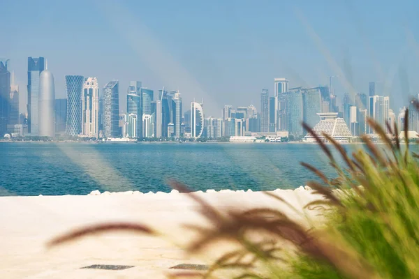 Vista panorámica del horizonte moderno de Doha con césped verde y playa en primer plano. Concepto de medio ambiente saludable — Foto de Stock