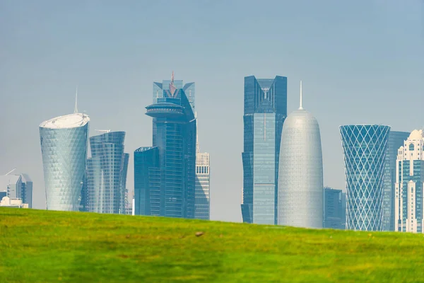 Vista panorámica del horizonte moderno de Doha con césped verde en primer plano. Concepto de medio ambiente saludable —  Fotos de Stock