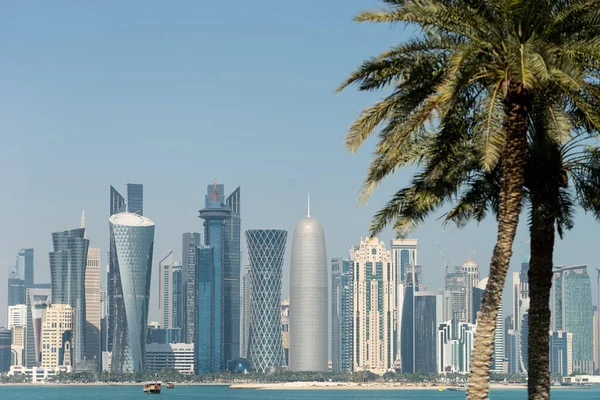 Vista panorámica del horizonte moderno de Doha a través de palmeras borrosas. Qatar en día soleado — Foto de Stock