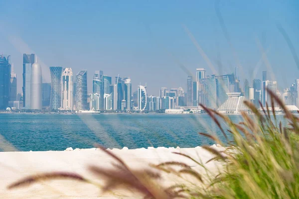 Vista panorámica del horizonte moderno de Doha con césped verde y playa en primer plano. Concepto de medio ambiente saludable — Foto de Stock