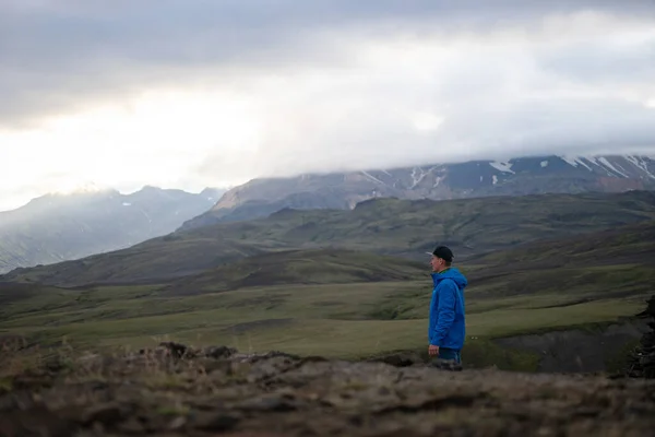 Backside of tall caucasian man wearing jacket standing in over snowy mountain on the Laugavegur track, Iceland. Promoting healthy lifestyle