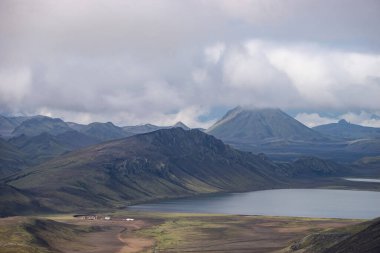 Hvanngil dağ kulübesi ve yeşil tepeli kamp alanı, nehir deresi ve göl manzaralı. Laugavegur yürüyüş yolu, İzlanda
