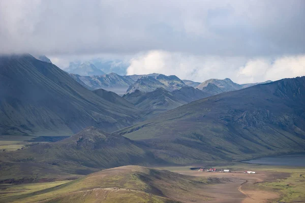 Kilátás a Hvanngil hegyi kunyhóra és kempingre zöld dombokkal, folyami patakkal és tóval. Laugavegur turistaút, Izland — Stock Fotó