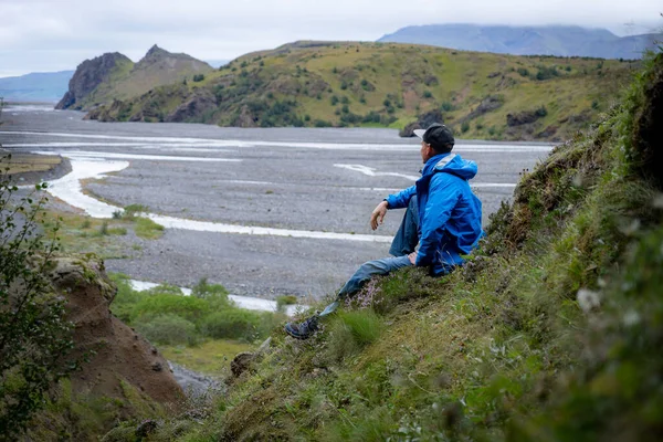 Chico joven caucásico sentado sobre fondo de montaña y cañón en el camino del sendero Laugavegur, Islandia. Promover un estilo de vida saludable — Foto de Stock