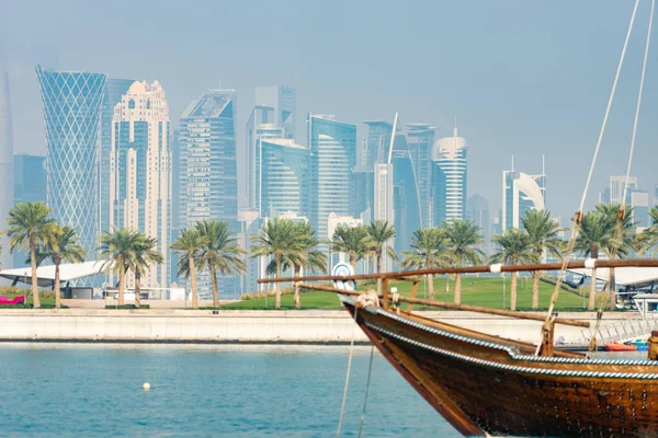 Barco histórico retro con vista panorámica borrosa del horizonte moderno de Doha y palmeras verdes en el fondo — Foto de Stock