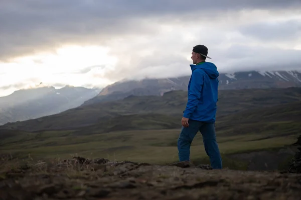 Позаду високого кавказського чоловіка, одягненого в куртку, стоїть над сніжною горою на трасі Лаугавегур, Ісландія. Сприяти здоровому способу життя — стокове фото