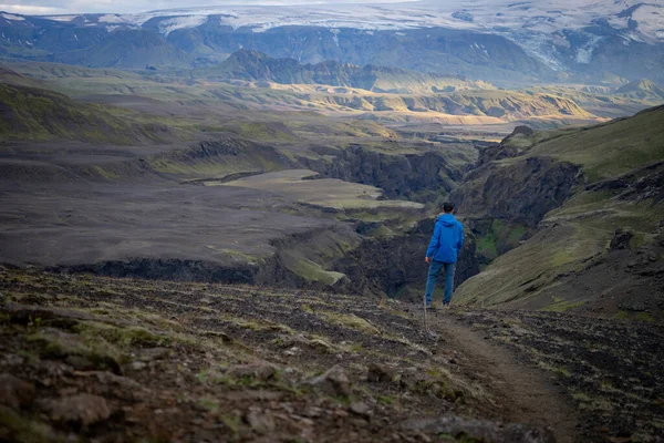 Backside of tall caucasian man wearing jacket standing in over snowy mountain on the Laugavegur track, Iceland. Promoting healthy lifestyle