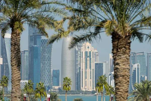 Blick auf die moderne Skyline von Doha durch verschwommene Palmen. Katar an sonnigem Tag — Stockfoto