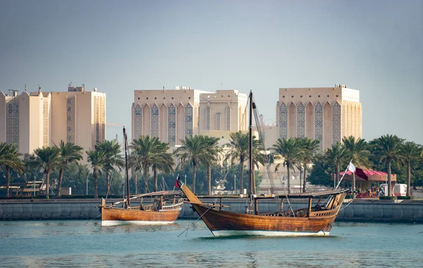 Ретро историческая лодка с размытым панорамным видом на современный горизонт Дохи и зеленые пальмы на заднем плане — стоковое фото