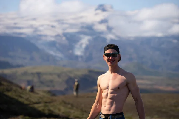 背の高い筋肉白人男性裸の胴が山と空の背景に立っています — ストック写真