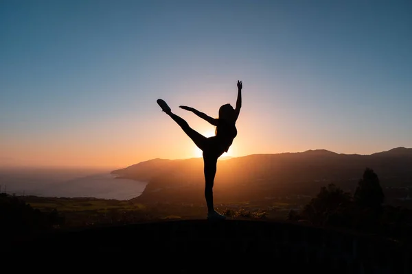 Silueta de mujer bailando al atardecer con montañas y mar sobre fondo — Foto de Stock