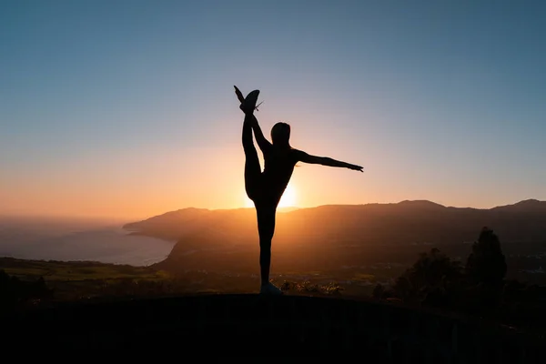 Silueta de mujer disfrutando de la libertad sintiéndose feliz al atardecer con montañas y mar sobre fondo — Foto de Stock