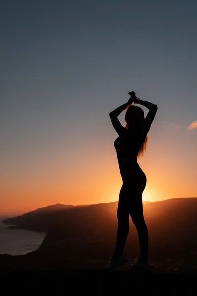 Silhouette di donna godendo la libertà sensazione felice al tramonto con montagne e mare sullo sfondo — Foto Stock