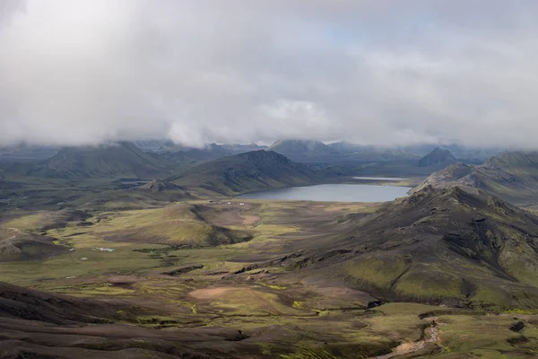 Widok na dolinę górską z zielonymi wzgórzami, strumień rzeczny i jezioro. Ścieżka turystyczna Laugavegur, Islandia — Zdjęcie stockowe