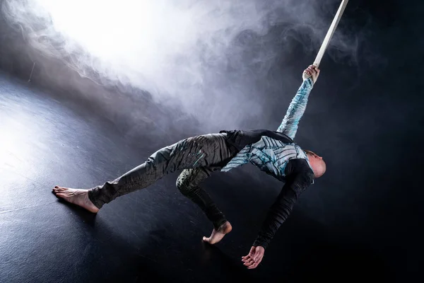 Artista de circo en las correas aéreas con traje en el fondo negro y ahumado. Concepto de sufrimiento, desesperación y derrota — Foto de Stock