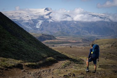 Laugavegur yürüyüş yolunun dağ ve sis arka planında duran uzun beyaz sırtlı sırt çantasının arkasında. İzlanda
