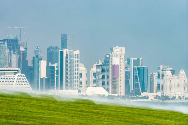 Vista panorámica del horizonte moderno de Doha con césped verde en primer plano. Concepto de medio ambiente saludable — Foto de Stock