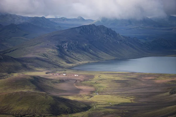 Kilátás a Hvanngil hegyi kunyhóra és kempingre zöld dombokkal, folyami patakkal és tóval. Laugavegur turistaút, Izland — Stock Fotó