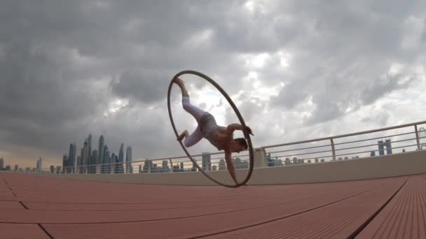 Artista Cyr Wheel com fundo cityscape de Dubai durante o pôr do sol — Vídeo de Stock