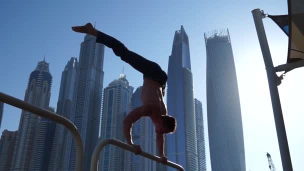 迪拜，一个肌肉男在街上做运动，背景是摩天大楼的都市景观。健康生活方式和现代概念 — 图库视频影像